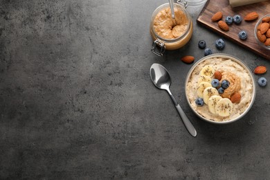 Photo of Tasty oatmeal porridge with toppings served on grey table, flat lay. Space for text