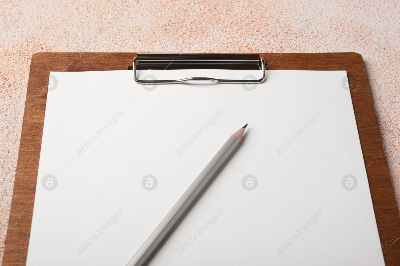 Photo of New clipboard with sheet of blank paper and pencil on color textured table, closeup