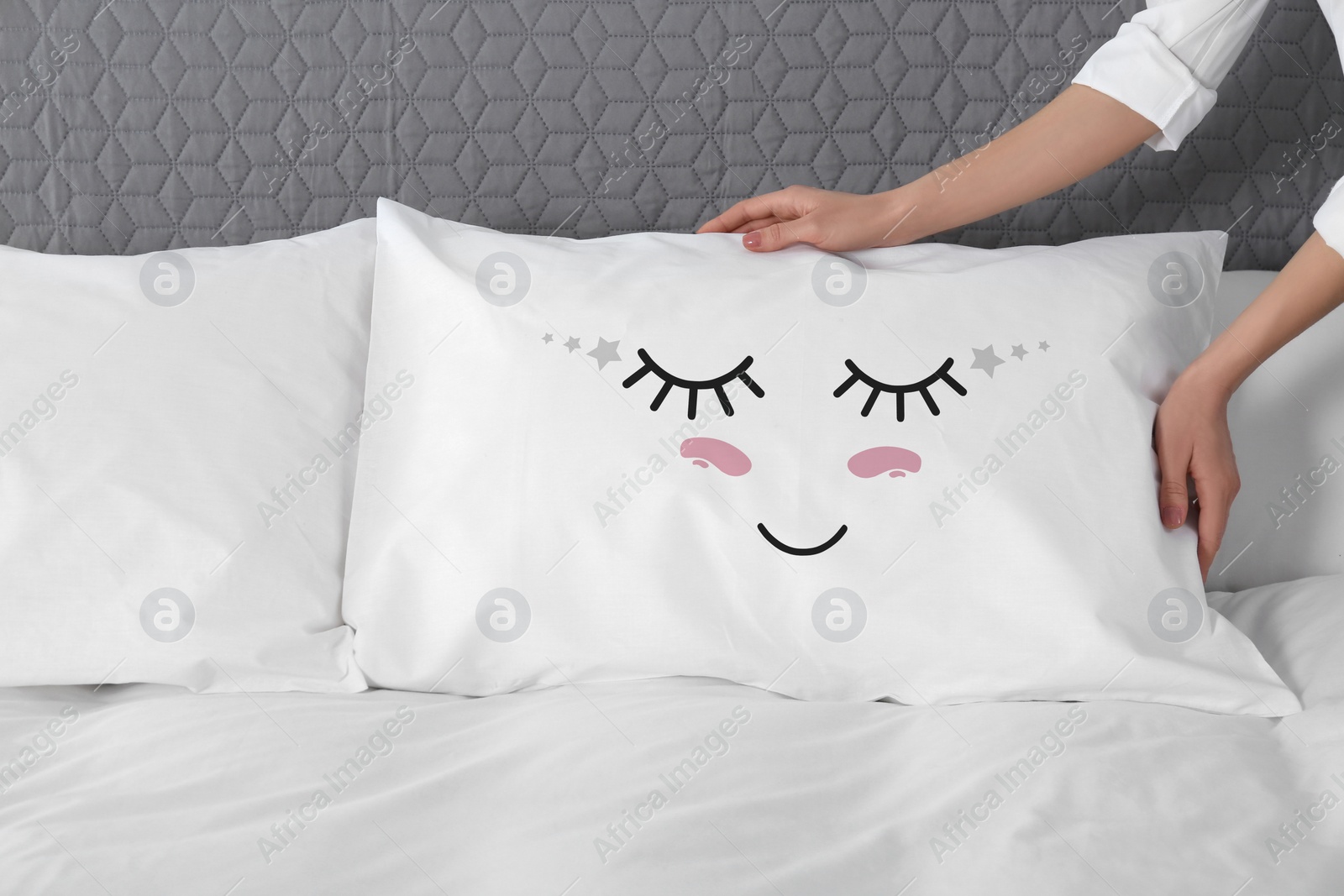 Image of Woman plumping pillow with cute face in bedroom, closeup