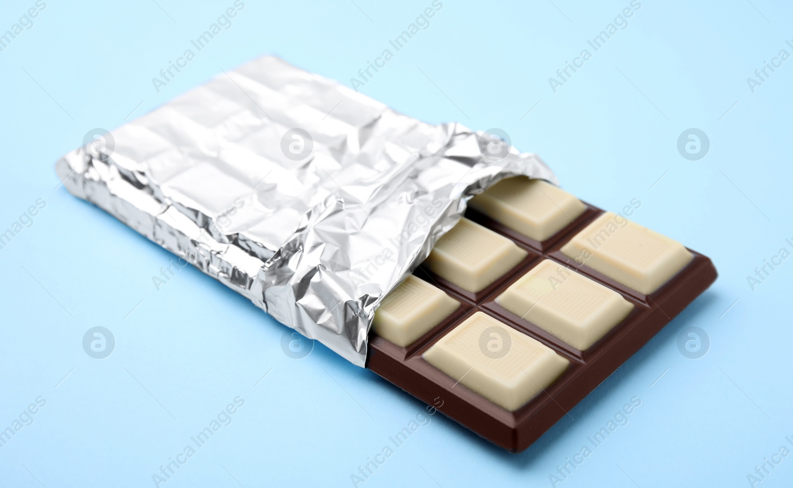 Photo of One tasty chocolate bar on light blue background