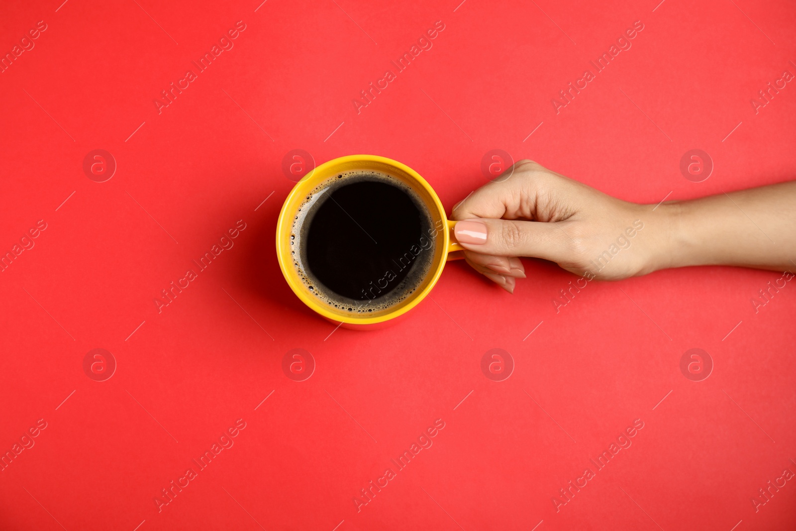 Photo of Woman with cup of coffee on red background, top view