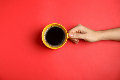 Woman with cup of coffee on red background, top view