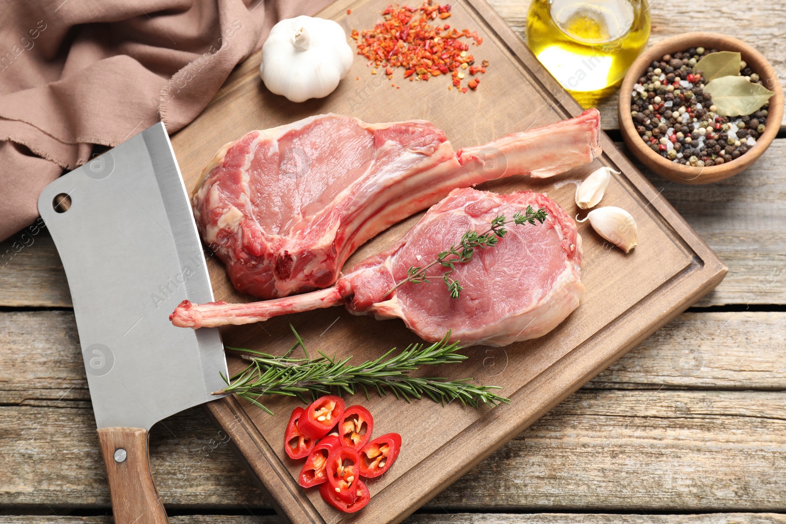 Photo of Fresh tomahawk beef cuts, butcher knife and spices on wooden table, top view