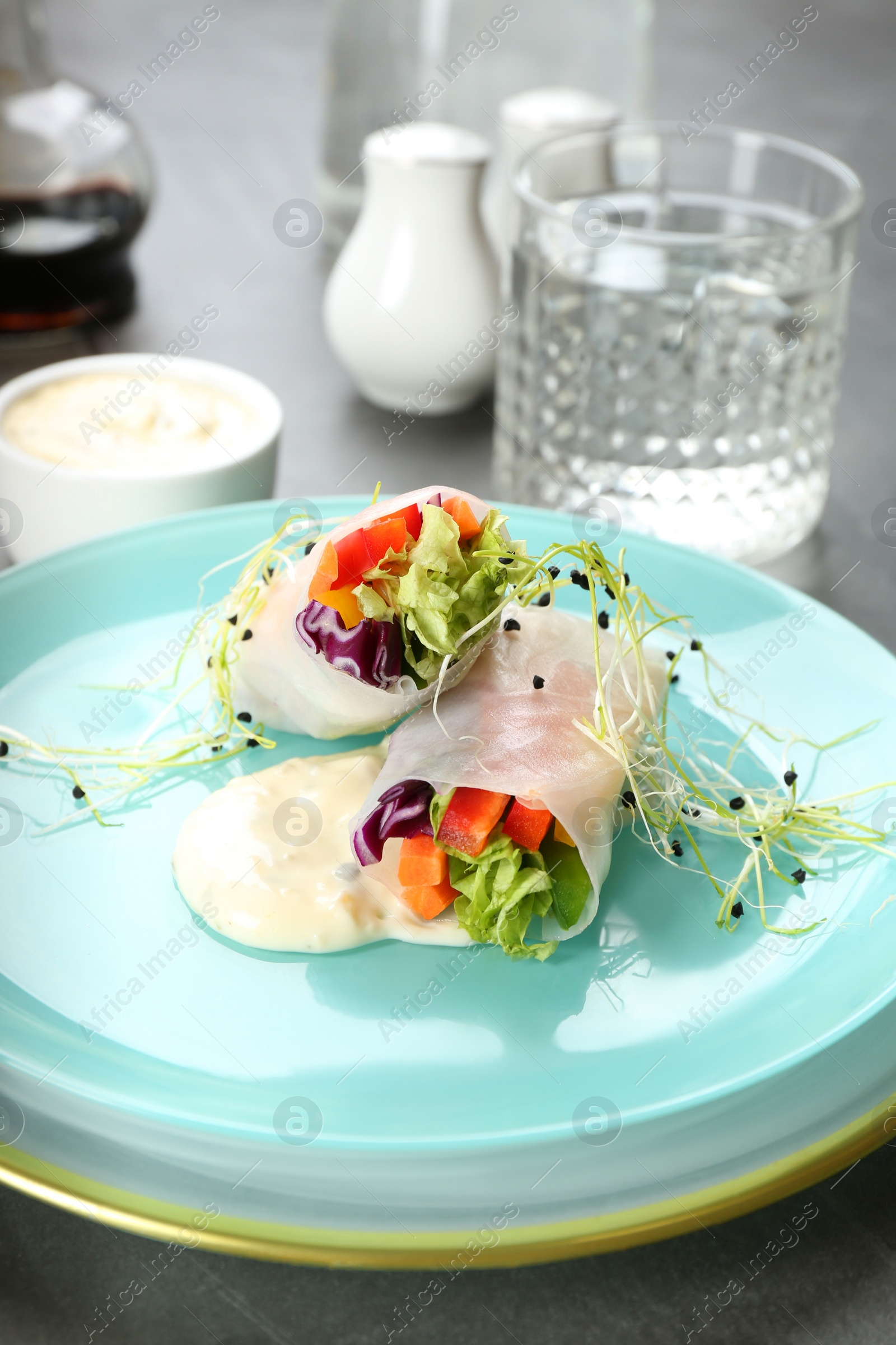 Photo of Delicious rolls wrapped in rice paper served on grey table