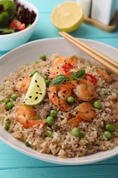 Photo of Tasty rice with shrimps and vegetables on turquoise wooden table, closeup