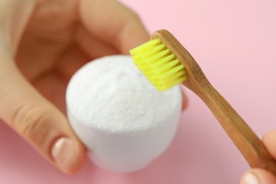 Young woman with toothbrush and bowl of baking soda at pink background, closeup