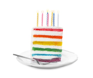 Photo of Slice of delicious rainbow cake with candles on white background