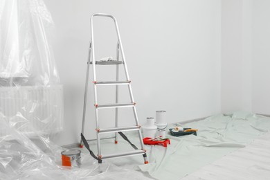 Photo of Metallic folding ladder and painting tools indoors