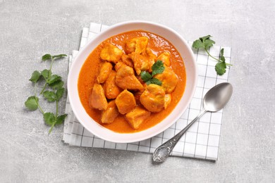 Photo of Bowl of delicious chicken curry on light grey table, flat lay