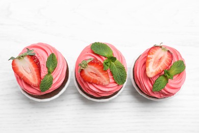 Photo of Sweet cupcakes with Strawberries on white wooden table, flat lay