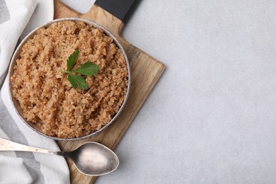 Photo of Tasty wheat porridge with parsley in bowl and spoon on light table, top view. Space for text