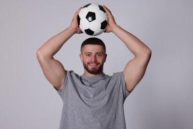 Photo of Athletic young man with soccer ball on light grey background