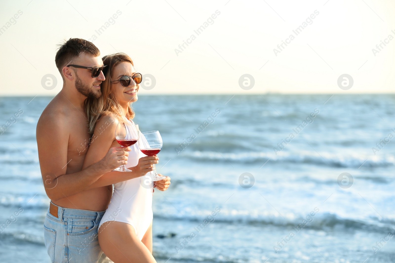 Photo of Young couple with glasses of wine on beach