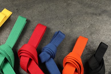 Photo of Colorful karate belts on gray background, flat lay. Space for text