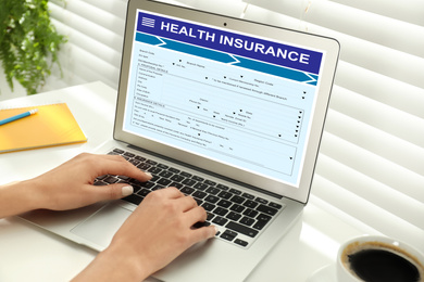 Woman with modern laptop indoors, closeup. Health insurance