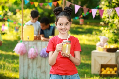 Photo of Cute little girl with natural lemonade in park. Summer refreshing drink