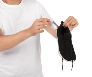 Photo of Man putting capsule shoe freshener in footwear on white background