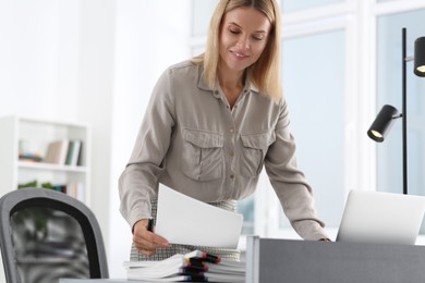 Photo of Happy woman working with documents at table in modern office