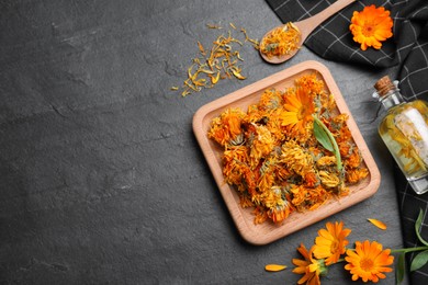 Dry and fresh calendula flowers with tincture on black table, flat lay. Space for text