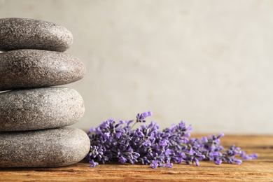 Photo of Lavender flowers and spa stones on wooden table, closeup. Space for text