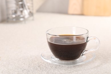 Delicious coffee in cup on light textured table, closeup. Space for text