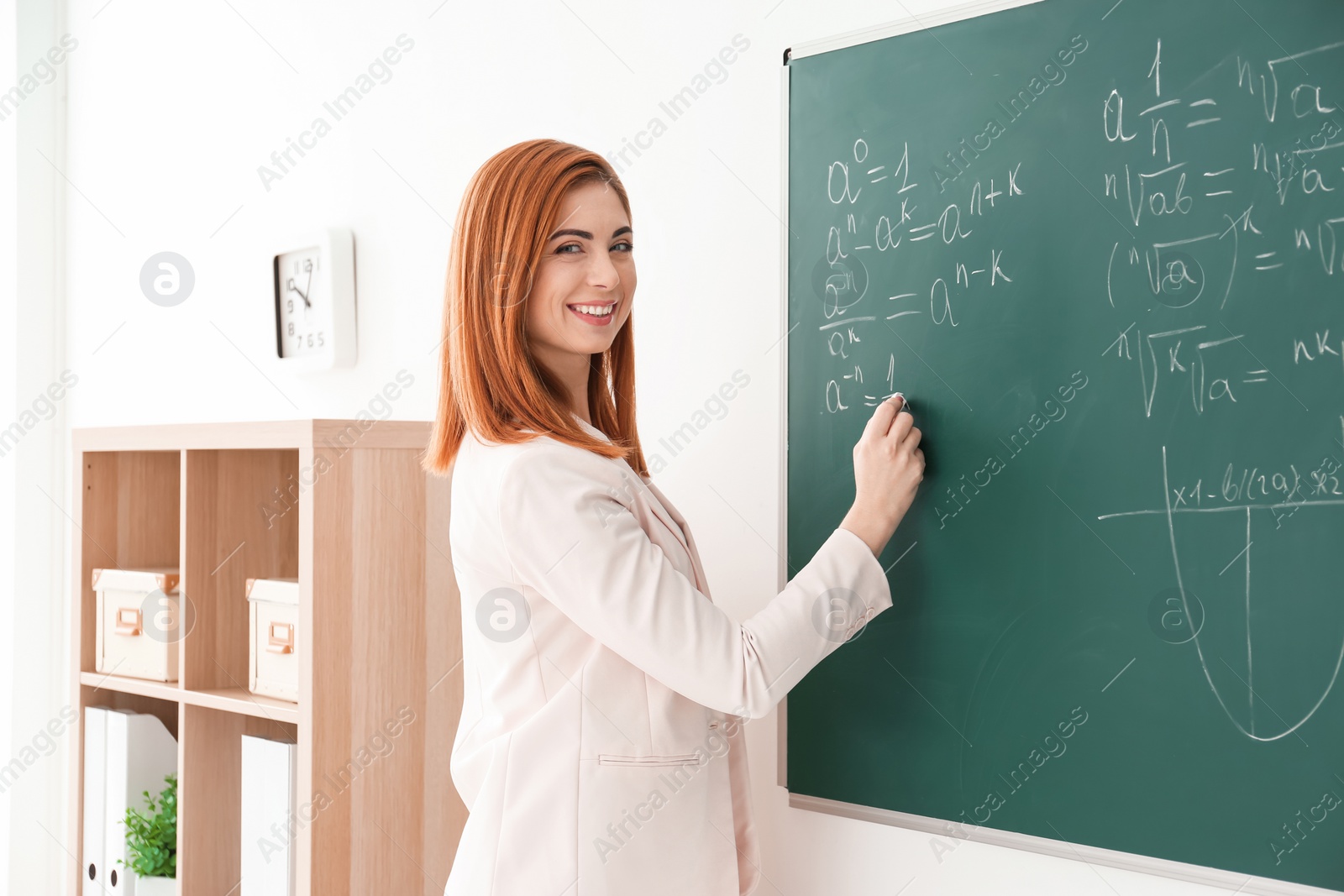 Photo of Beautiful young teacher writing on blackboard in classroom