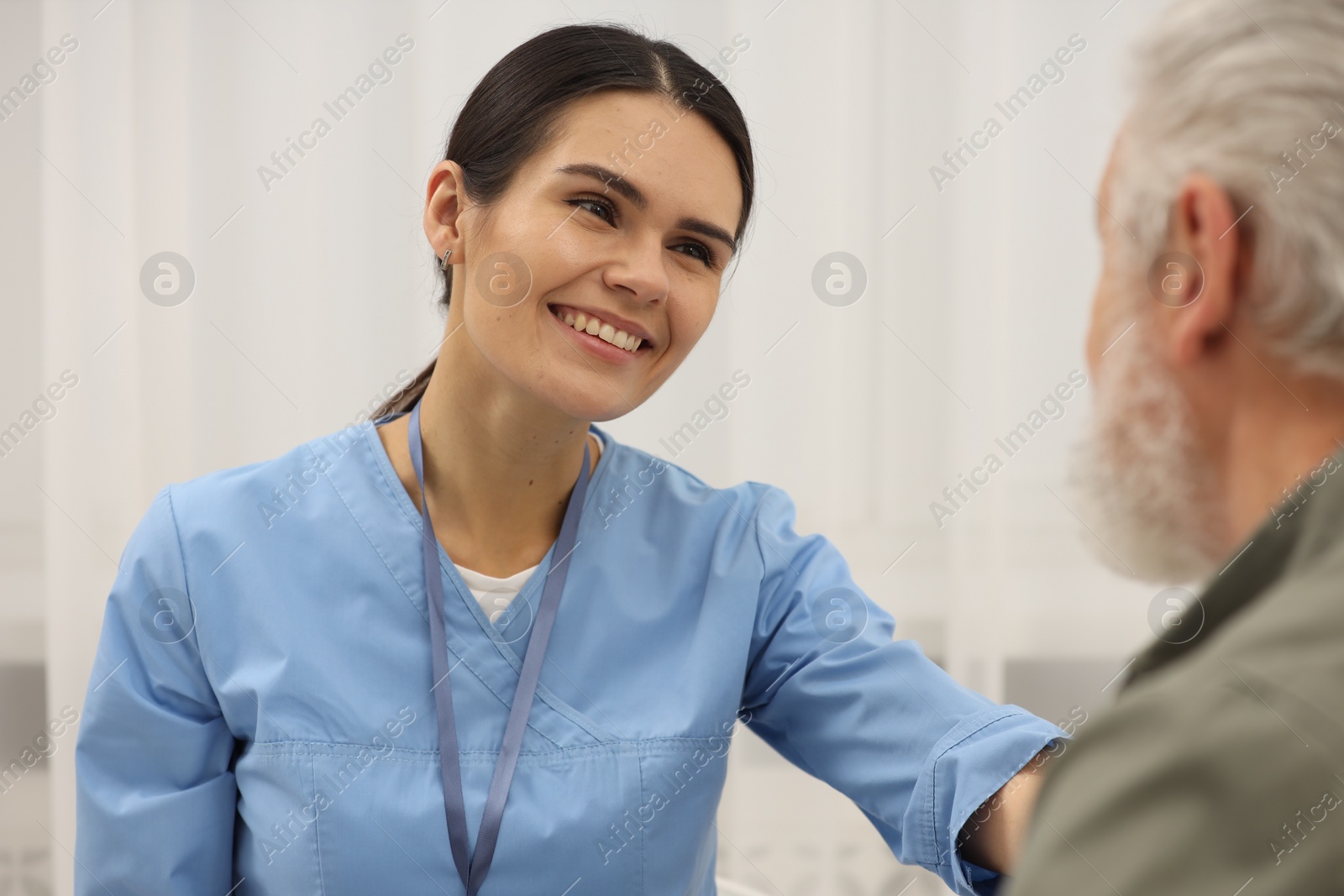 Photo of Smiling nurse supporting elderly patient in hospital