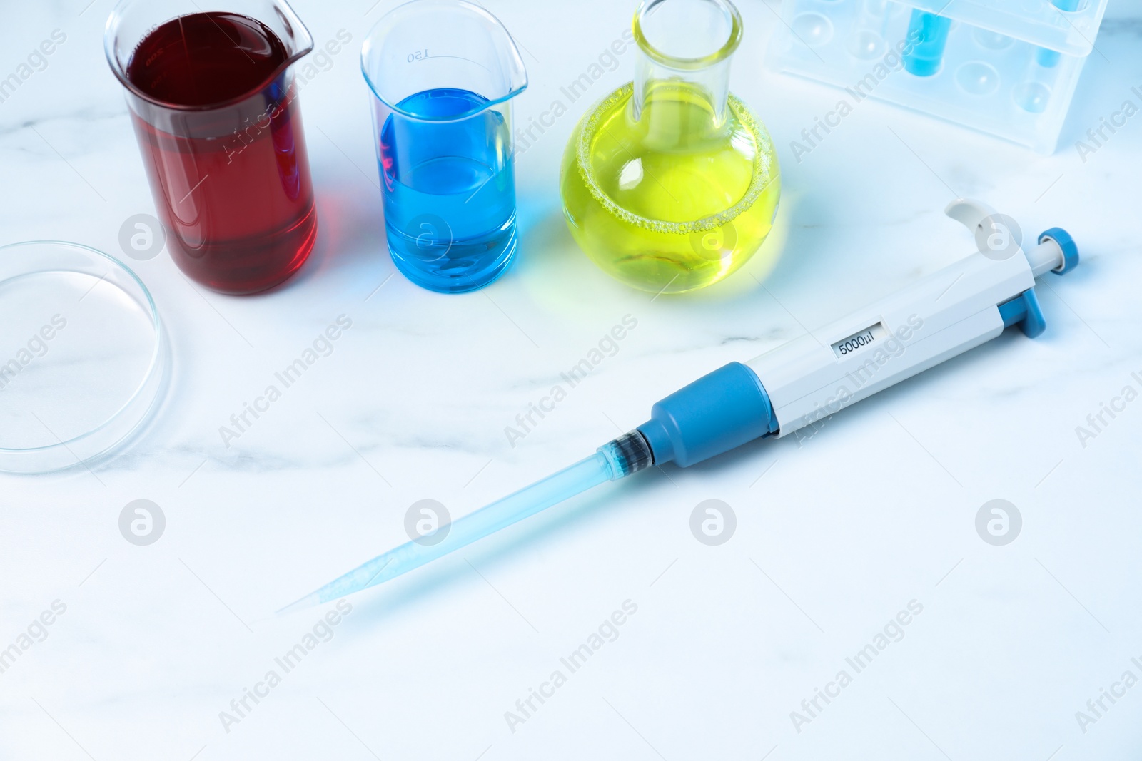 Photo of Laboratory analysis. Micropipette, petri dish and other glassware on white marble table