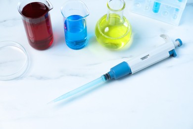 Photo of Laboratory analysis. Micropipette, petri dish and other glassware on white marble table