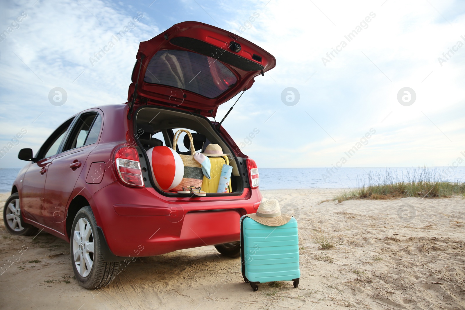 Photo of Red car luggage on beach, space for text. Summer vacation trip