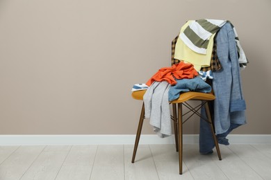 Photo of Different clothes on chair near light grey wall, space for text