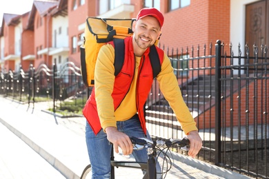 Photo of Male courier on bicycle delivering food in city