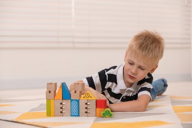 Photo of Cute little boy playing with wooden toys indoors, space for text