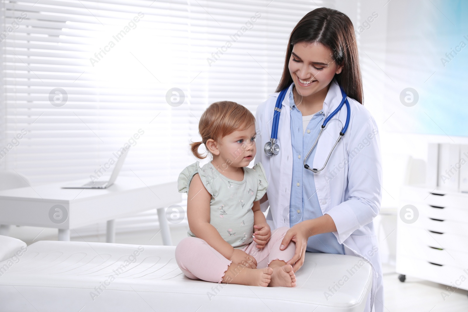 Photo of Pediatrician examining cute little baby in clinic