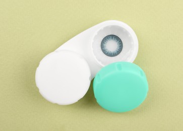 Photo of Case with blue contact lenses on light green background, top view