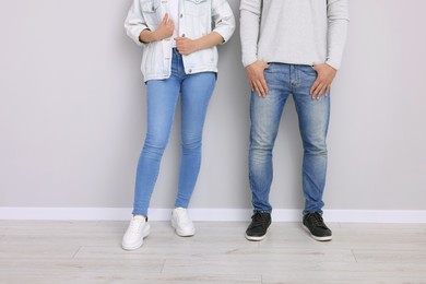 Photo of People in stylish jeans near light grey wall indoors, closeup