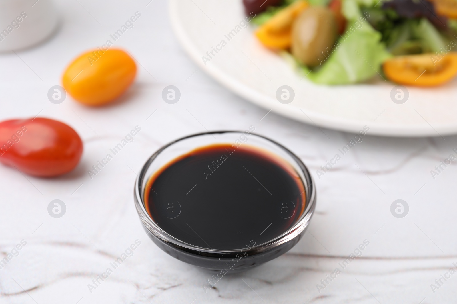 Photo of Vinegar in bowl on light textured table, closeup