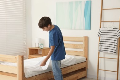 Boy changing bed linens in children room