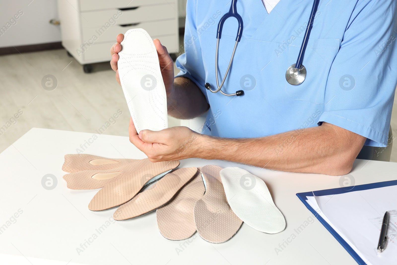 Photo of Male orthopedist showing insoles in hospital, closeup