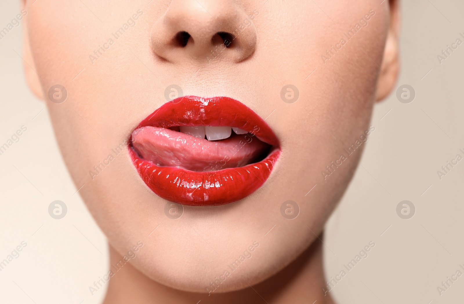 Photo of Beautiful young woman with red glossy lips on color background, closeup