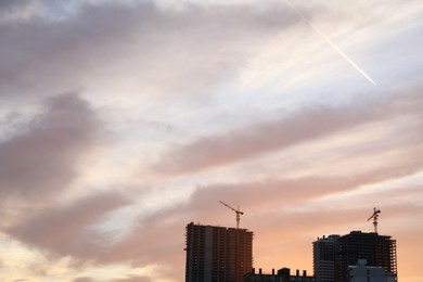 Tower cranes near unfinished buildings in city