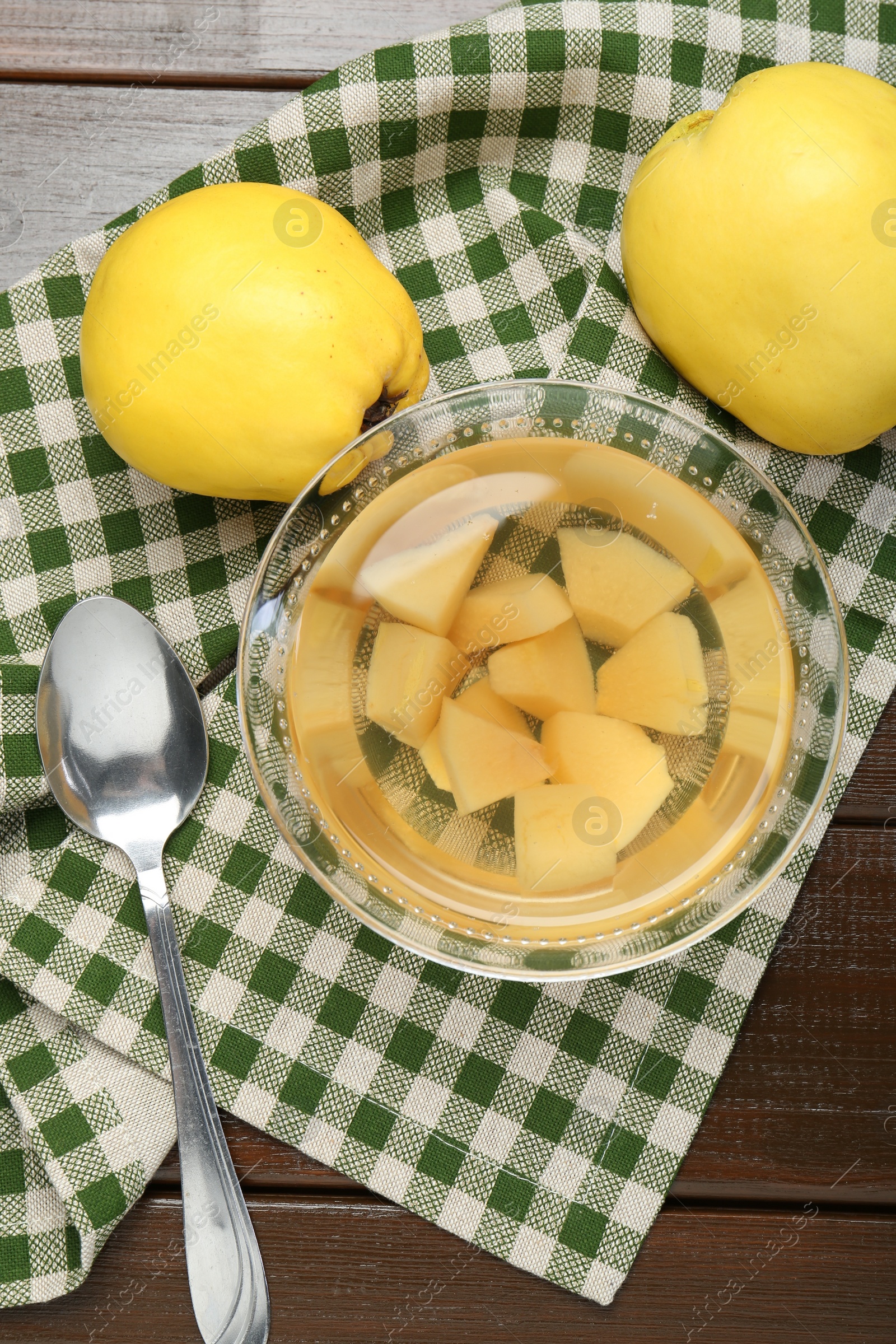 Photo of Delicious quince drink in glass bowl, fresh fruits and spoon on wooden table, top view