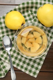 Photo of Delicious quince drink in glass bowl, fresh fruits and spoon on wooden table, top view