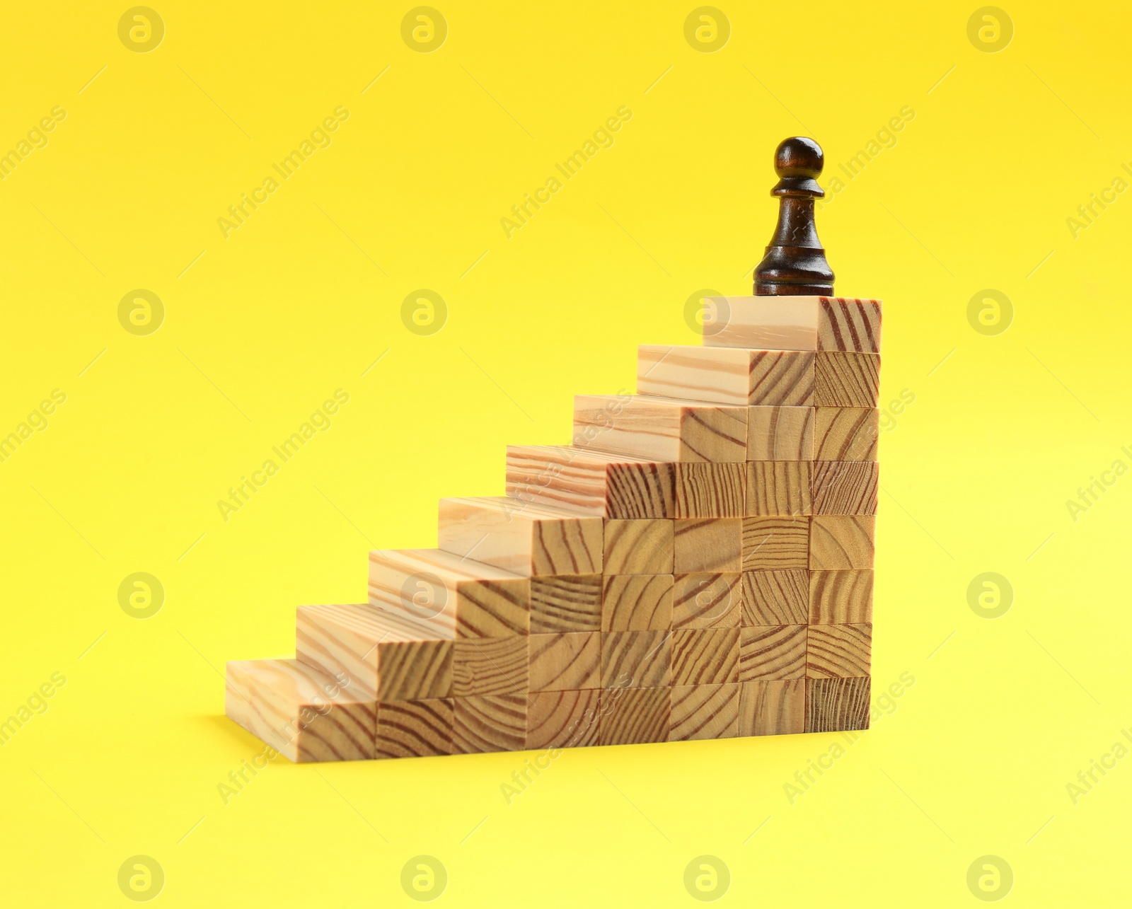 Photo of Pawn on top of stairs on yellow background. Career promotion concept