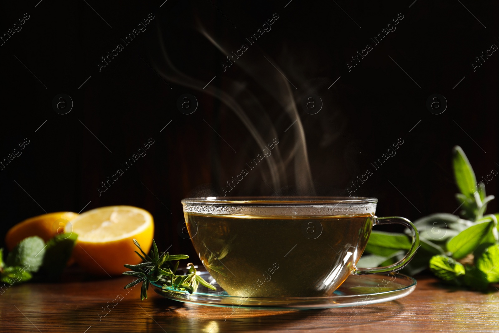Photo of Cup of aromatic herbal tea and rosemary on wooden table