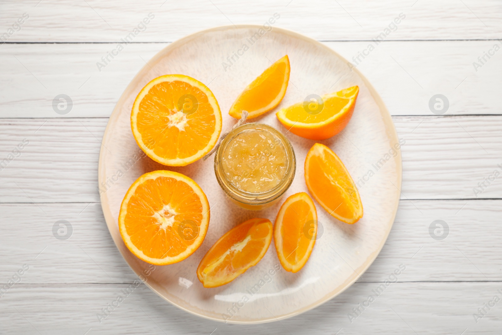 Photo of Jar of delicious orange jam and fresh fruits on white wooden table, top view