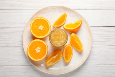 Photo of Jar of delicious orange jam and fresh fruits on white wooden table, top view