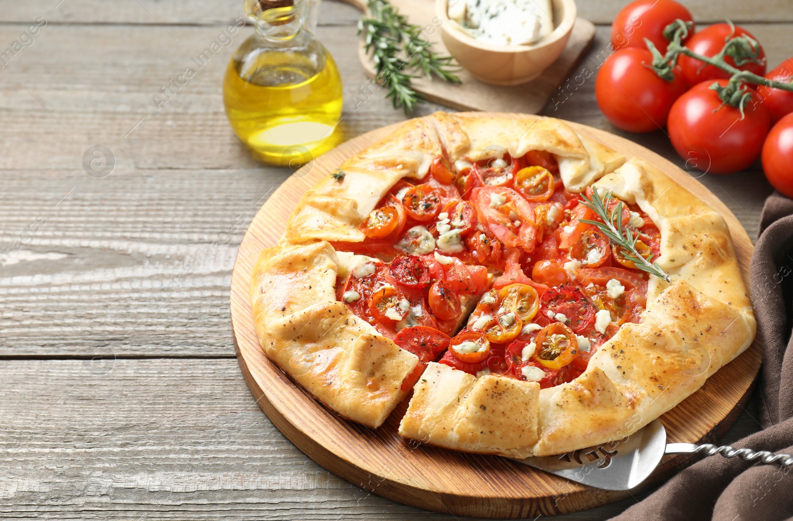 Photo of Tasty galette with tomato, rosemary and cheese (Caprese galette) on wooden table, closeup. Space for text