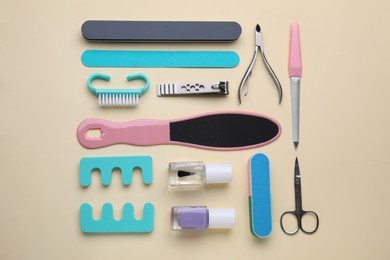 Photo of Set of pedicure tools on beige background, flat lay