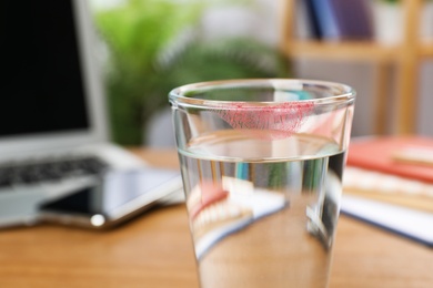 Photo of Glass of water with lipstick mark at workplace, closeup